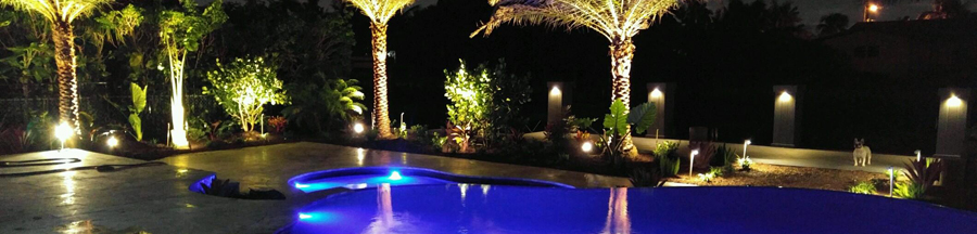 night-time view of large swimming pool and travertine deck with lighting inside and around the swimming pool